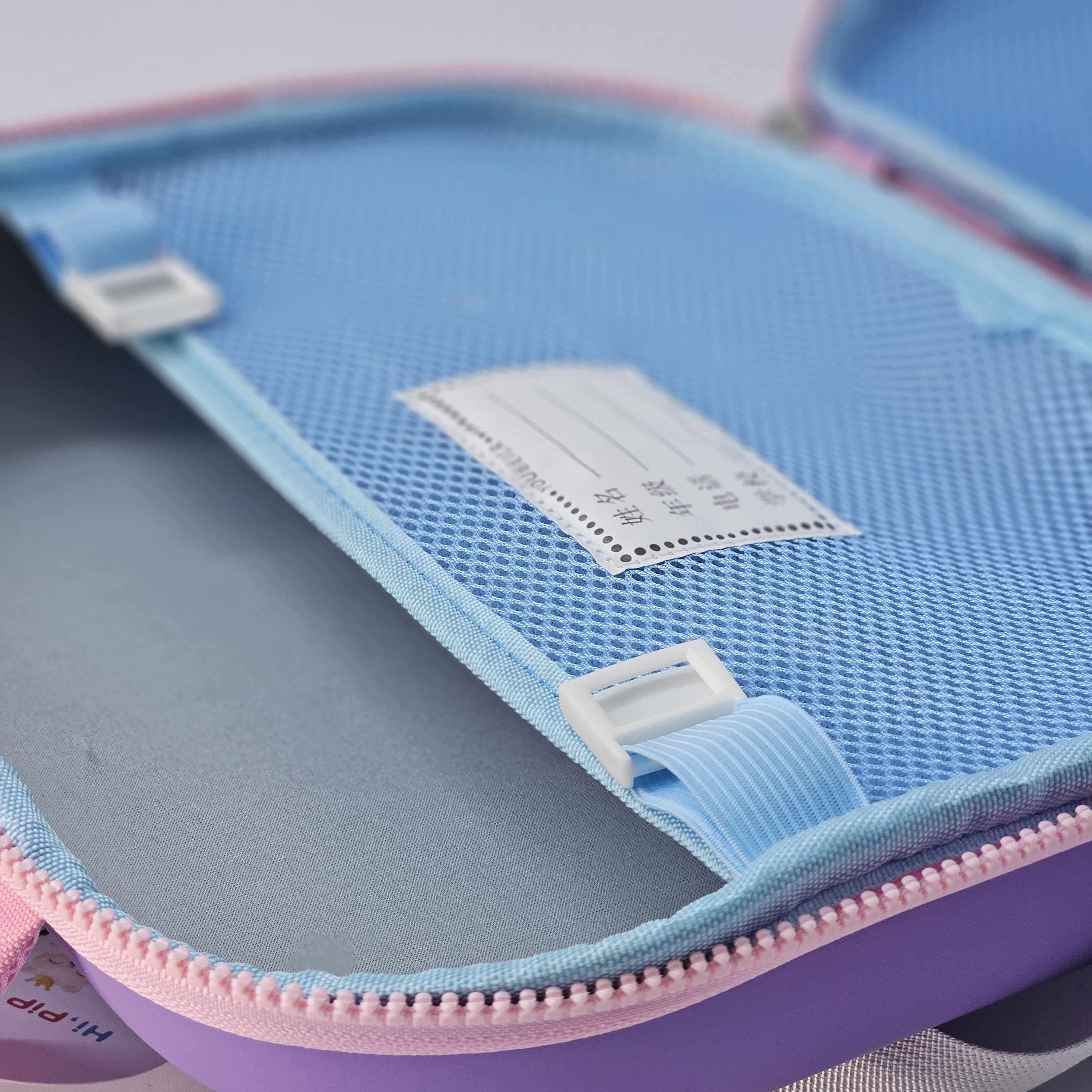 Close-up of a blue and pink pencil case with a label inside.